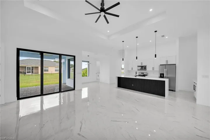 Kitchen featuring light tile flooring, hanging light fixtures, a raised ceiling, white cabinets, and appliances with stainless steel finishes
