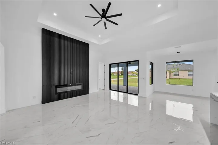 Tiled spare room with a large fireplace and a raised ceiling
