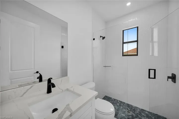 Bathroom with a tile shower, vanity, and toilet