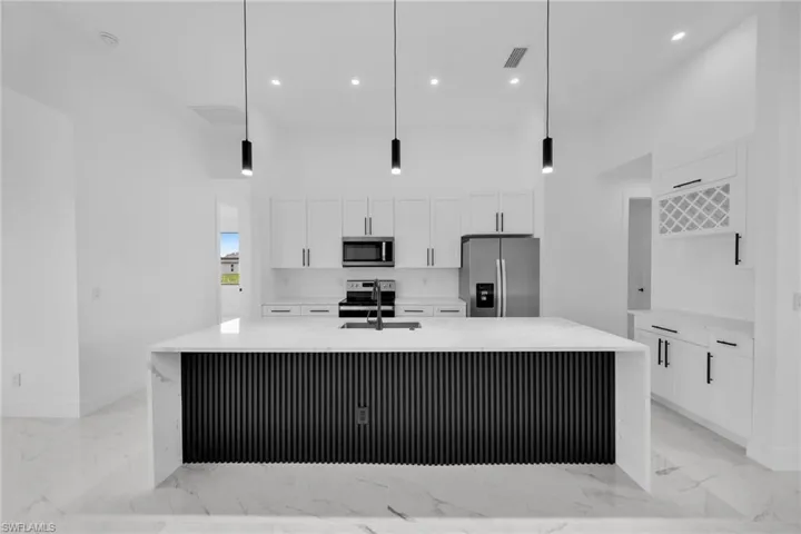 Kitchen with pendant lighting, a spacious island, white cabinetry, and appliances with stainless steel finishes