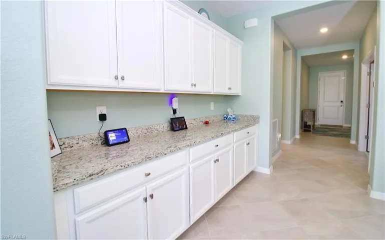 Kitchen featuring white cabinetry, light stone countertops, and light tile patterned floors