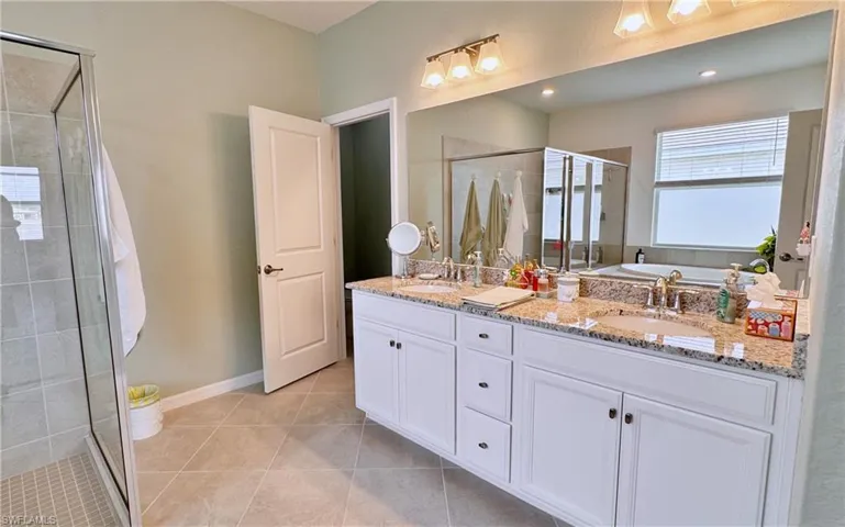 Bathroom featuring tile patterned floors, shower with separate bathtub, and vanity