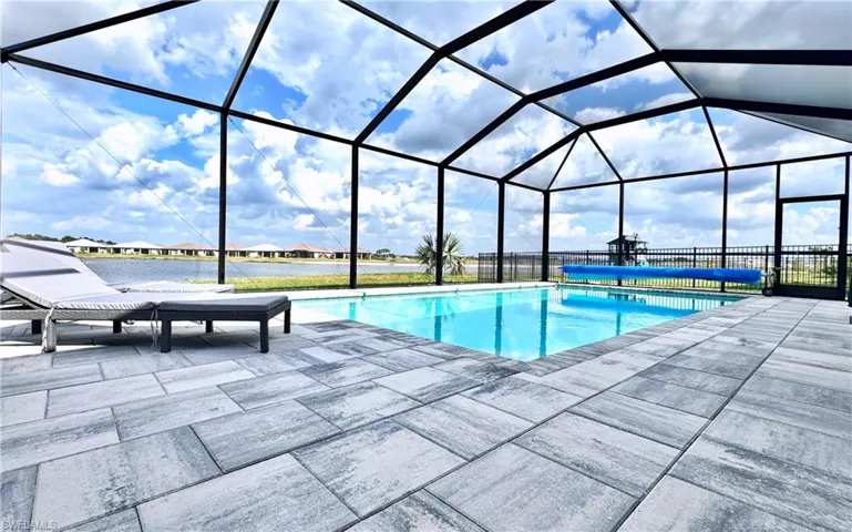 View of pool featuring a water view, glass enclosure, and a patio area