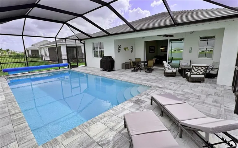View of pool featuring area for grilling, a patio, ceiling fan, and glass enclosure