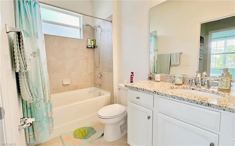 Full bathroom featuring shower / bathtub combination with curtain, vanity, a wealth of natural light, and toilet