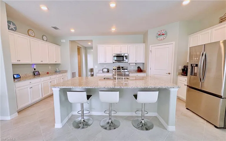 Kitchen with white cabinetry, sink, stainless steel appliances, and a center island with sink