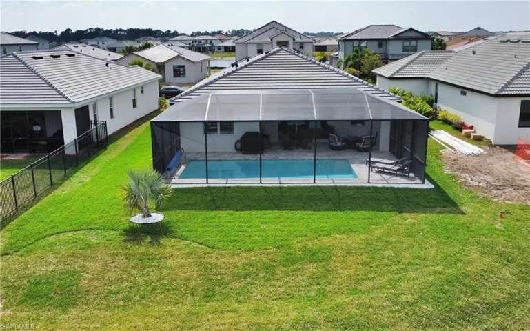Rear view of property with a yard, a lanai, a fenced in pool, and a patio