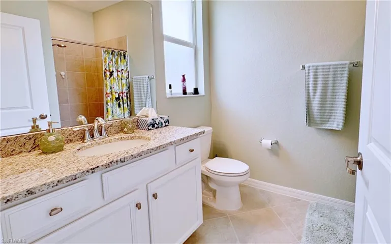 Bathroom featuring vanity, walk in shower, tile patterned floors, and toilet