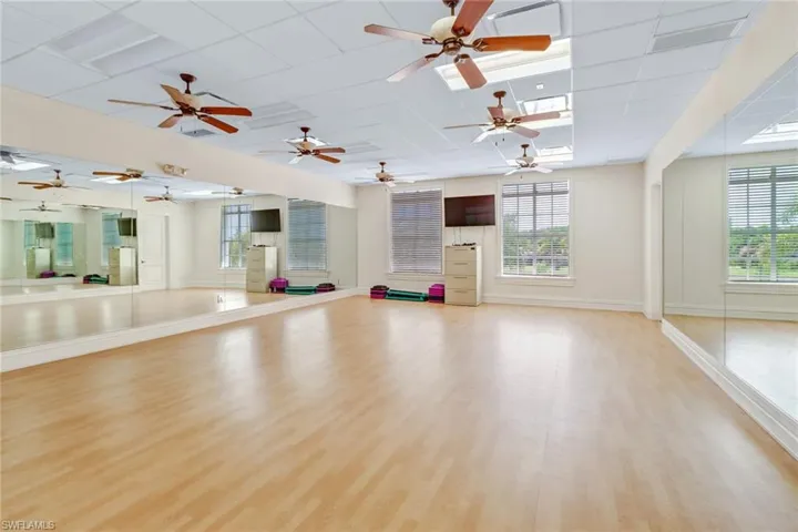 Workout area featuring plenty of natural light, light wood finished floors, baseboards, and a drop ceiling