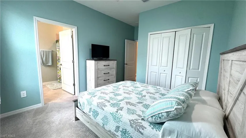 Carpeted bedroom with ensuite bath and a closet