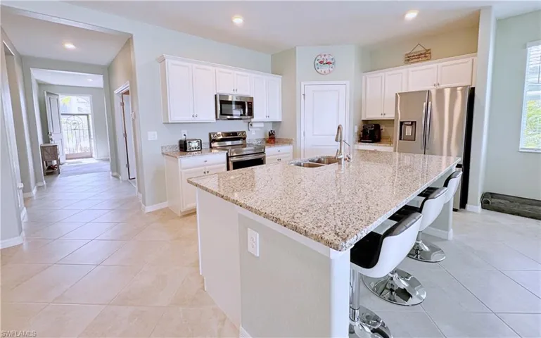 Kitchen with sink, stainless steel appliances, an island with sink, and white cabinets