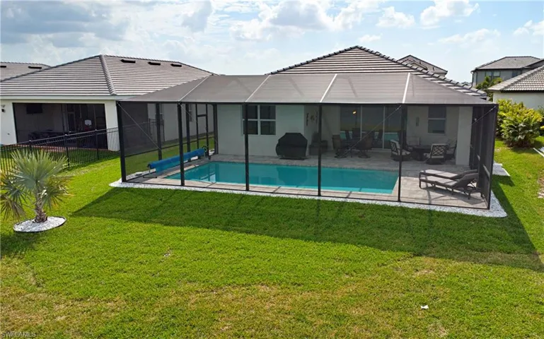 Rear view of property with a fenced in pool, a lanai, a patio area, and a lawn