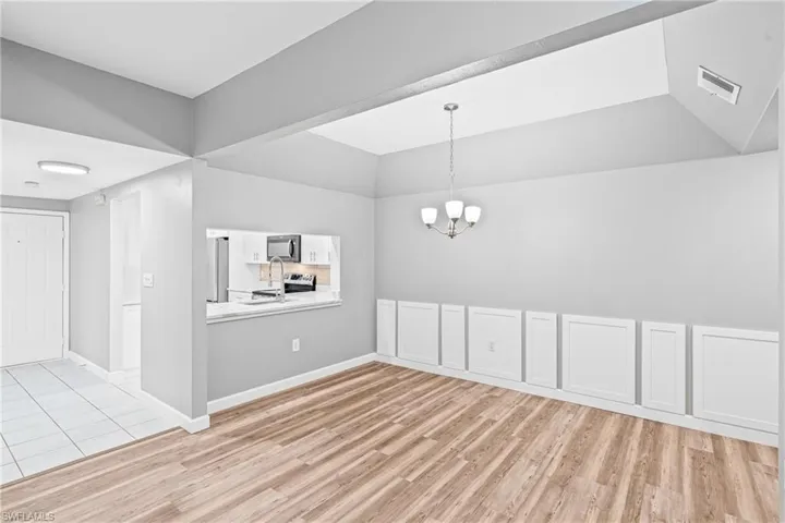 Unfurnished dining area with light wood-style floors, a chandelier, and lofted ceiling