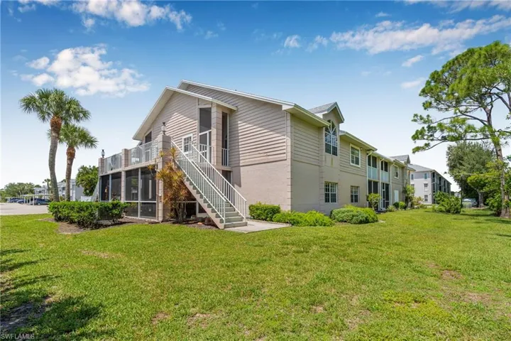 Back of property with stairway, a yard, and a balcony