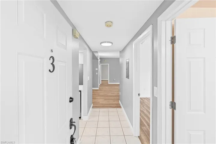 Hall with light tile patterned flooring and baseboards