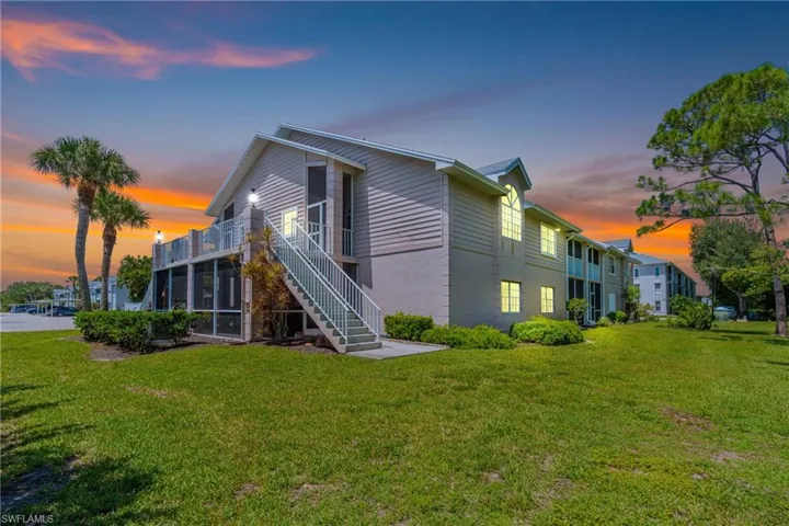 Rear view of house featuring stairs, a yard, and a balcony