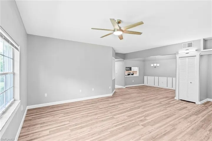 Unfurnished living room with a chandelier, light wood-style floors, and a ceiling fan