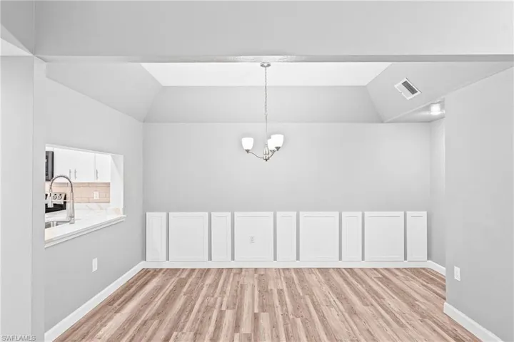 Unfurnished dining area with vaulted ceiling, light wood-style floors, and a chandelier