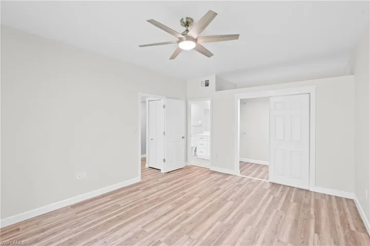 Unfurnished bedroom with a closet, light wood-style flooring, a ceiling fan, and connected bathroom