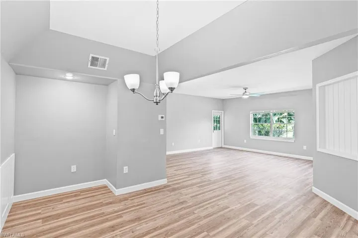 Empty room with a chandelier, light wood-style flooring, and ceiling fan
