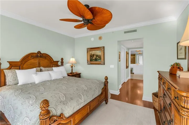Bedroom with hardwood / wood-style floors, connected bathroom, ceiling fan, and crown molding