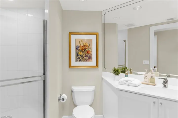 Bathroom featuring walk in shower, vanity, and toilet