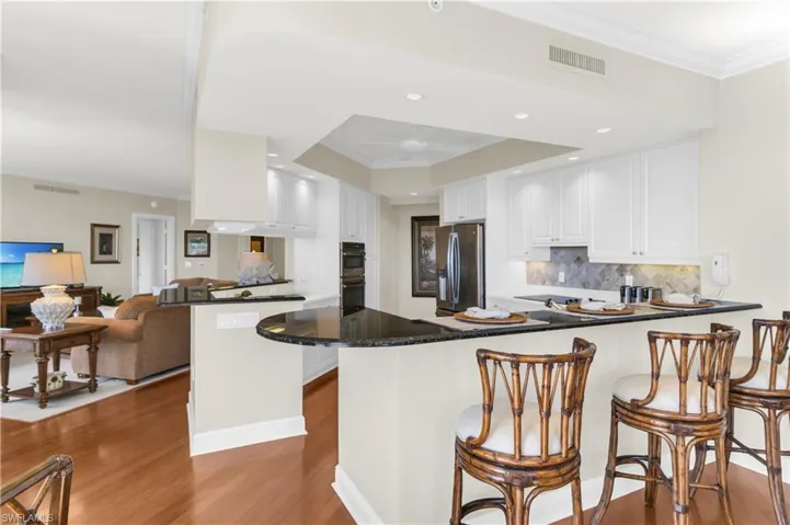 Kitchen featuring white cabinetry, kitchen peninsula, a breakfast bar, appliances with stainless steel finishes, and hardwood / wood-style flooring