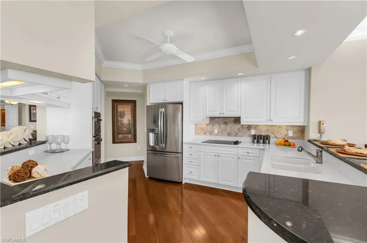 Kitchen featuring dark wood-type flooring, white cabinets, crown molding, sink, and stainless steel appliances