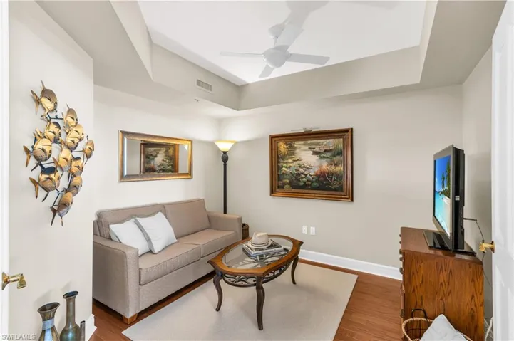 Living room featuring hardwood / wood-style flooring, ceiling fan, and a tray ceiling