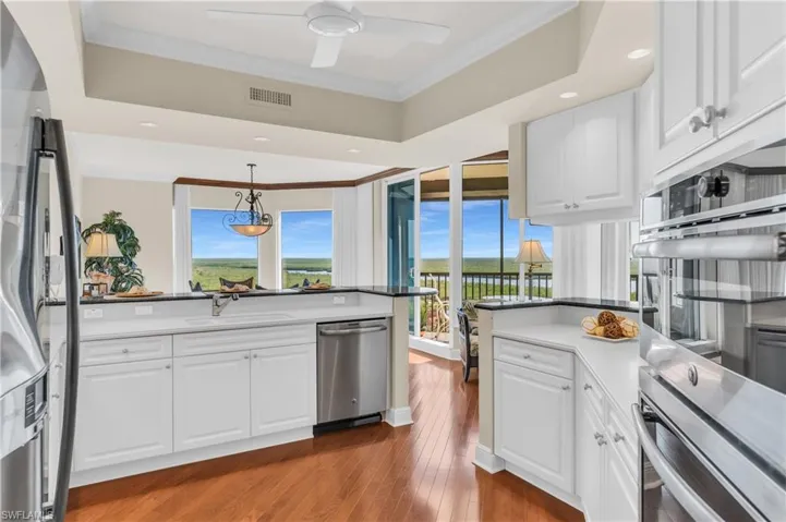 Kitchen with appliances with stainless steel finishes, dark hardwood / wood-style flooring, sink, decorative light fixtures, and white cabinetry