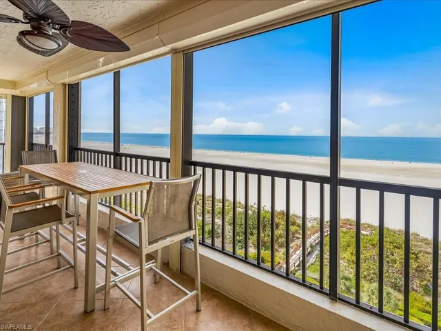 Sunroom / solarium with view of water and beach, tile patterned floors, and a textured ceiling
