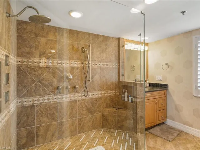 Full bath featuring a stall shower, vanity, light tile patterned flooring, and wallpapered walls
