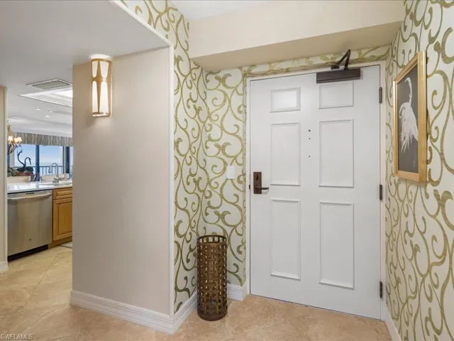 Foyer entrance with wallpapered walls, a chandelier, and light tile patterned floors