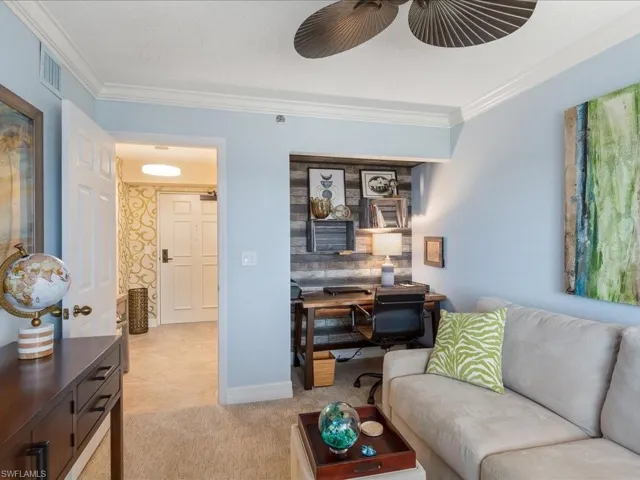 Living area with ornamental molding, an office area, light colored carpet, and a textured ceiling