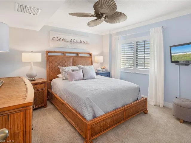 Carpeted bedroom with a ceiling fan and crown molding