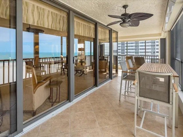 Sunroom with ceiling fan, a balcony, and a water view