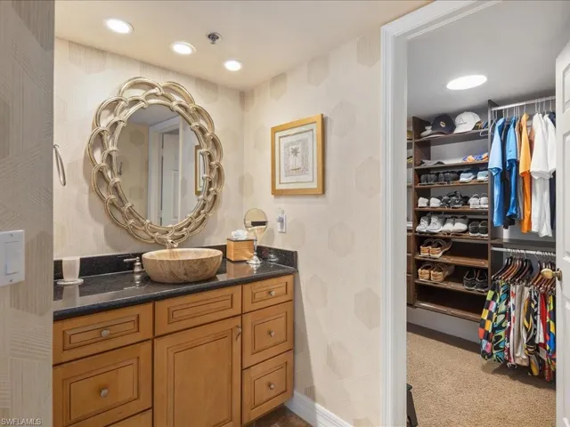 Bathroom with a walk in closet, vanity, recessed lighting, and carpet flooring