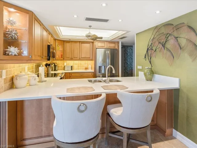 Kitchen featuring a kitchen bar, appliances with stainless steel finishes, decorative backsplash, a peninsula, and recessed lighting