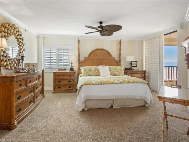 Bedroom featuring multiple windows, ornamental molding, light colored carpet, access to exterior, and a ceiling fan