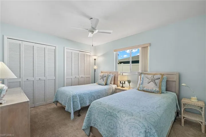 Carpeted bedroom featuring multiple closets and ceiling fan