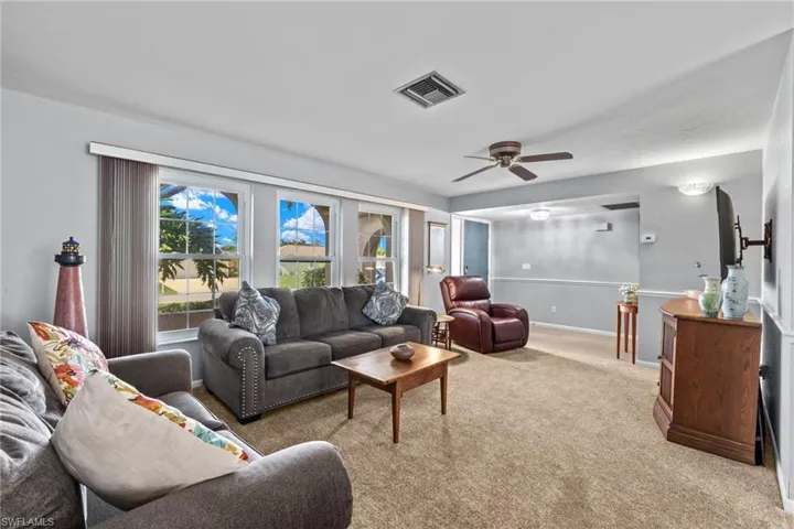 Carpeted living room featuring ceiling fan