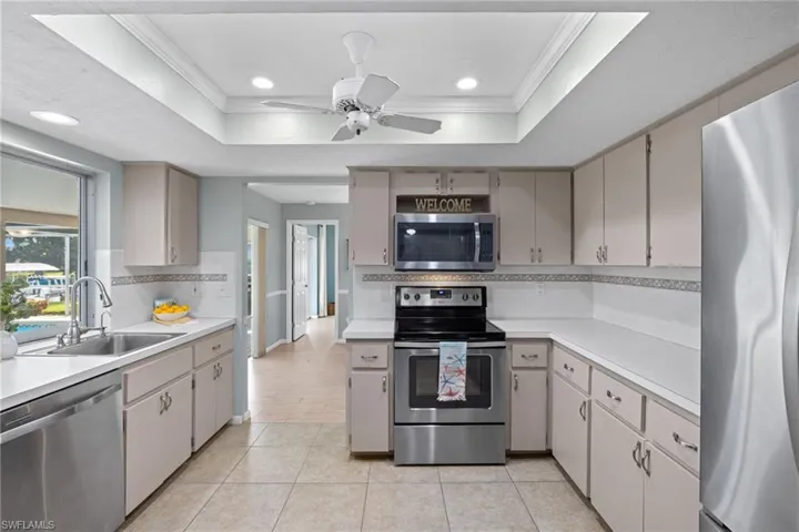 Kitchen with stainless steel appliances, sink, tasteful backsplash, and a raised ceiling