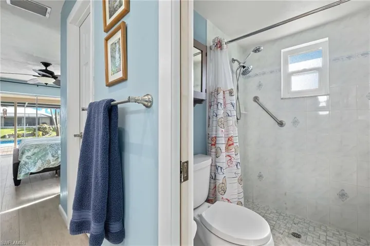 Bathroom with walk in shower, ceiling fan, wood-style flooring, and toilet