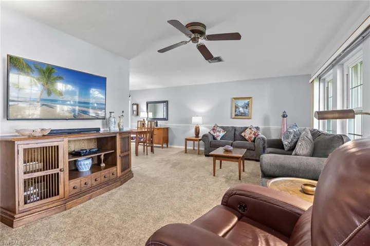 Carpeted living room with ceiling fan