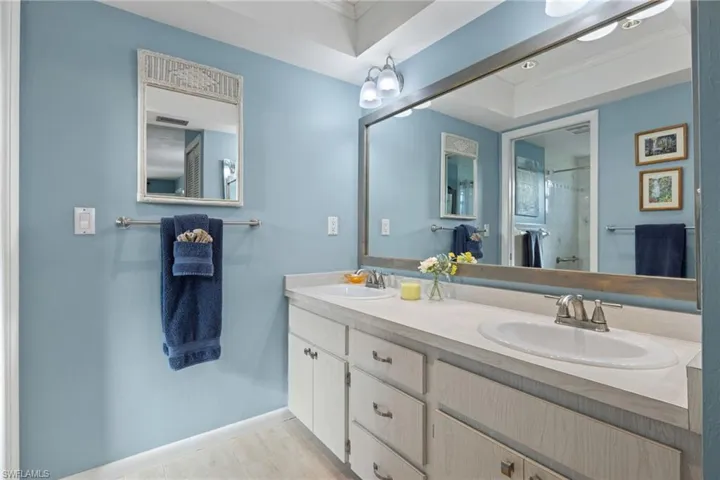 Bathroom featuring ornamental molding, large vanity, a raised ceiling, and dual sinks