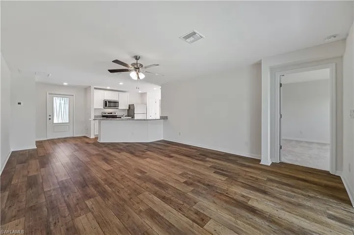 Unfurnished living room featuring dark hardwood / wood-style flooring and ceiling fan