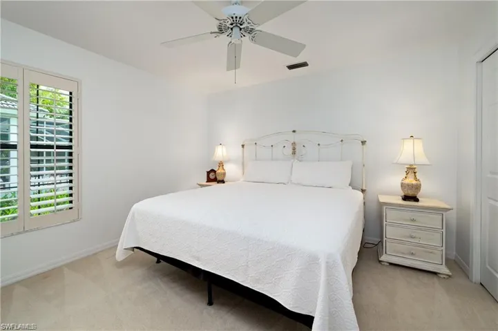 Bedroom featuring a ceiling fan, baseboards, visible vents, and light carpet