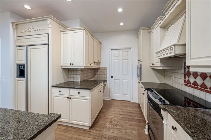 Kitchen with custom range hood, recessed lighting, light wood-type flooring, and built in appliances