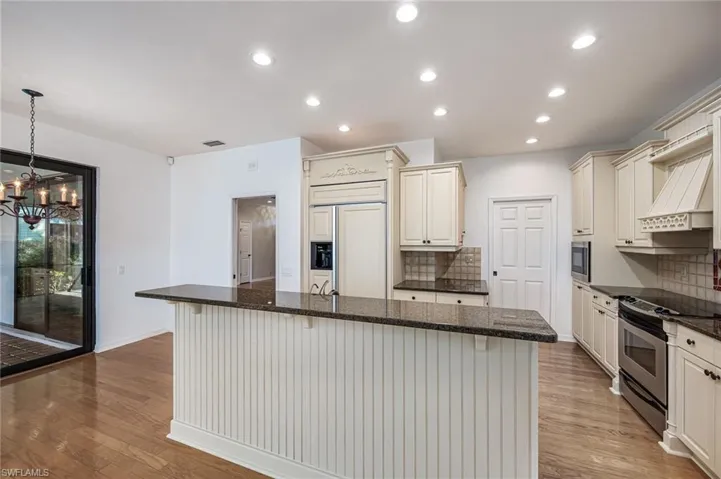 Kitchen featuring built in appliances, a kitchen breakfast bar, light wood-type flooring, and visible vents