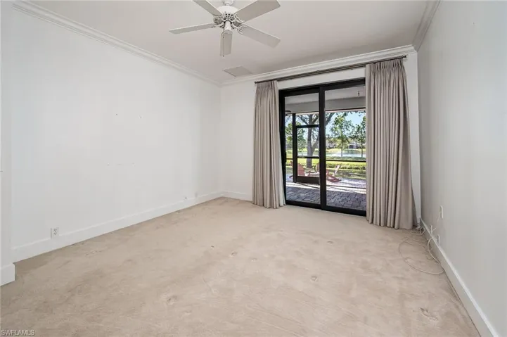 Primary bedroom unfurnished with sliding glass doors opening to the screened lanai and entertainment area on the patio
